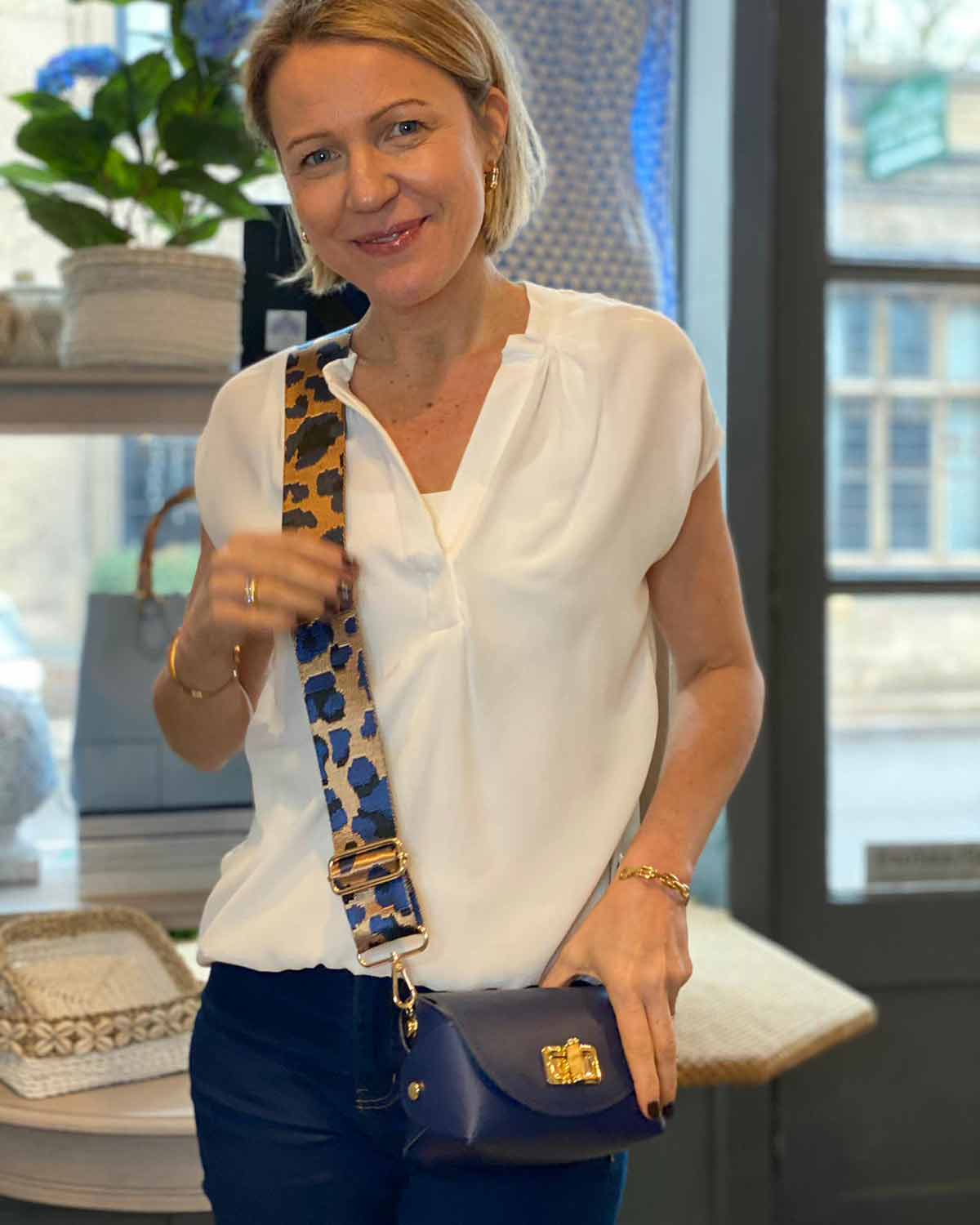 Emma with adjustable animal print bag strap attached to leather cross body bag with bamboo clasp.