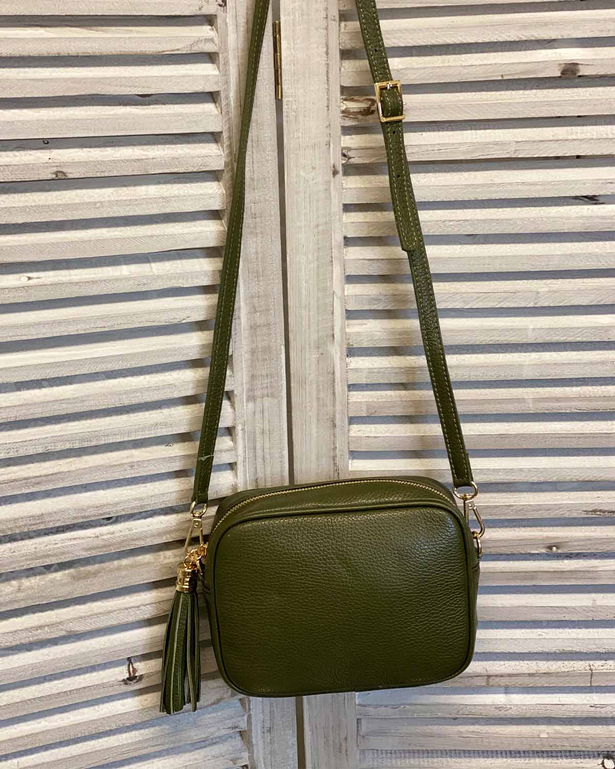 Khaki leather tassel bag with side tassel with adjustable long cross body strap.
