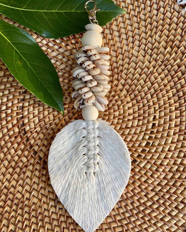 Shell keyring with a woven tassel pictured on a rattan placemat.