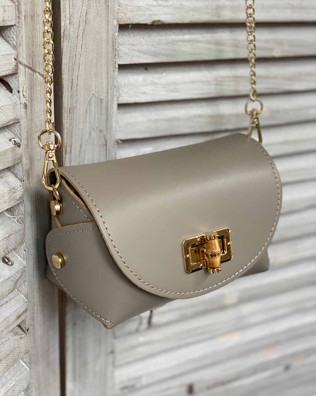 Taupe cross body bag with gold bamboo clasp. With adjustable clasps on the sides.