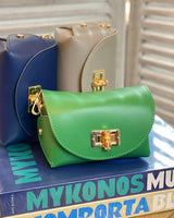 One green, one navy and one taupe cross body bags with gold bamboo clasp. Pictured on coffee table books.