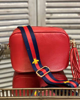 Red tassel bag with navy/red stripe print with bee detail going across it. On a mirrored table.