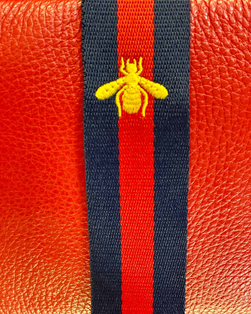 Close up image of red/navy stripe with bee detail bag strap.