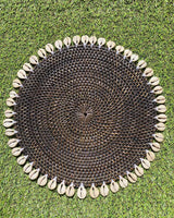 Table placemat in coloured black rattan edged with sea shells.