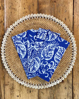 Set of four napkins printed with white leaf on blue rayon, on rattan shell placemat.
