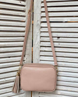 Blush pink leather tassel bag with side tassel with adjustable long cross body strap.