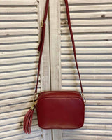 Burgundy leather tassel bag with side tassel with adjustable long cross body strap.