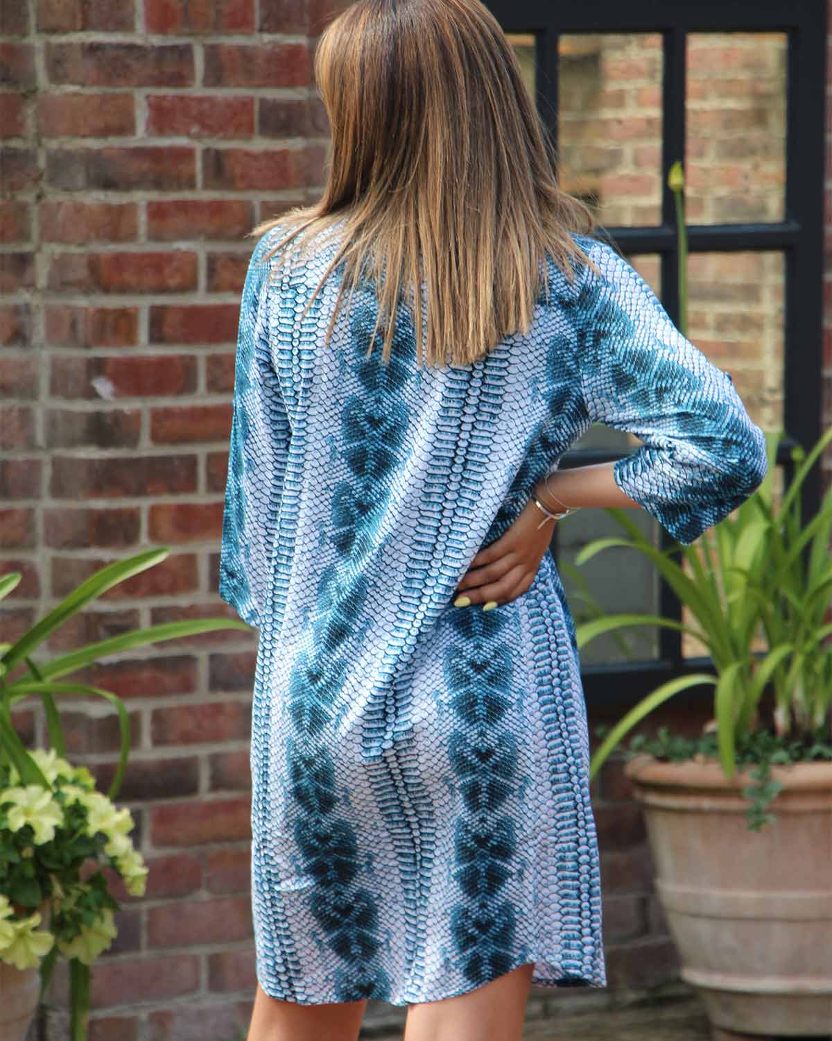 Woman in simple straight shirt dress printed with a navy and white snakeskin print. It has 3/4 sleeves and can be belted for a different look.