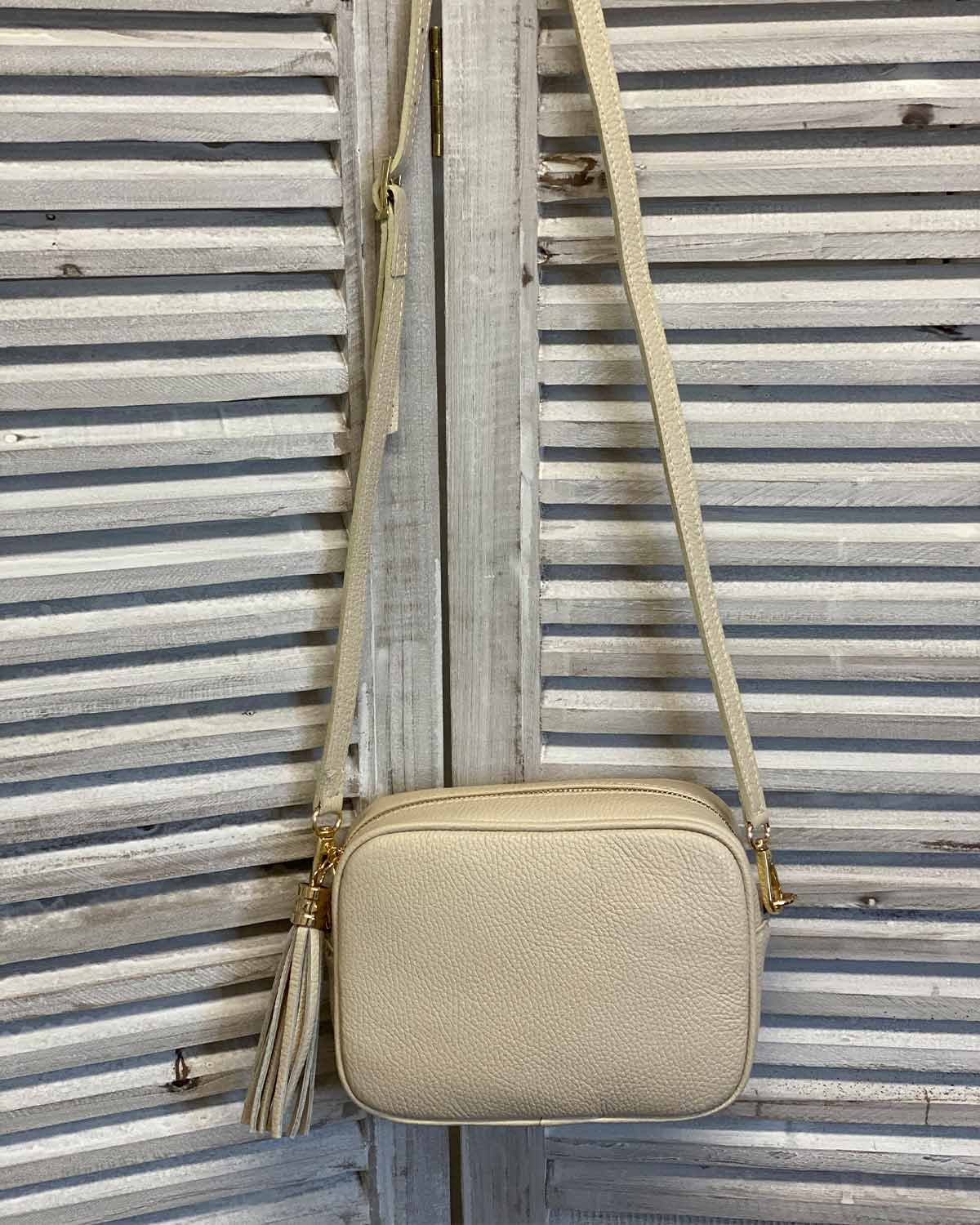 Cream leather tassel bag with side tassel with adjustable long cross body strap.