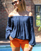 Woman in a navy top paired with a bright orange daisy shorts. They are a structured short with belt loops and zip fastening.