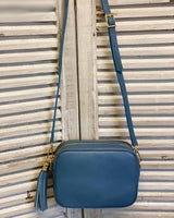 Denim blue lleather tassel bag with side tassel with adjustable long cross body strap.