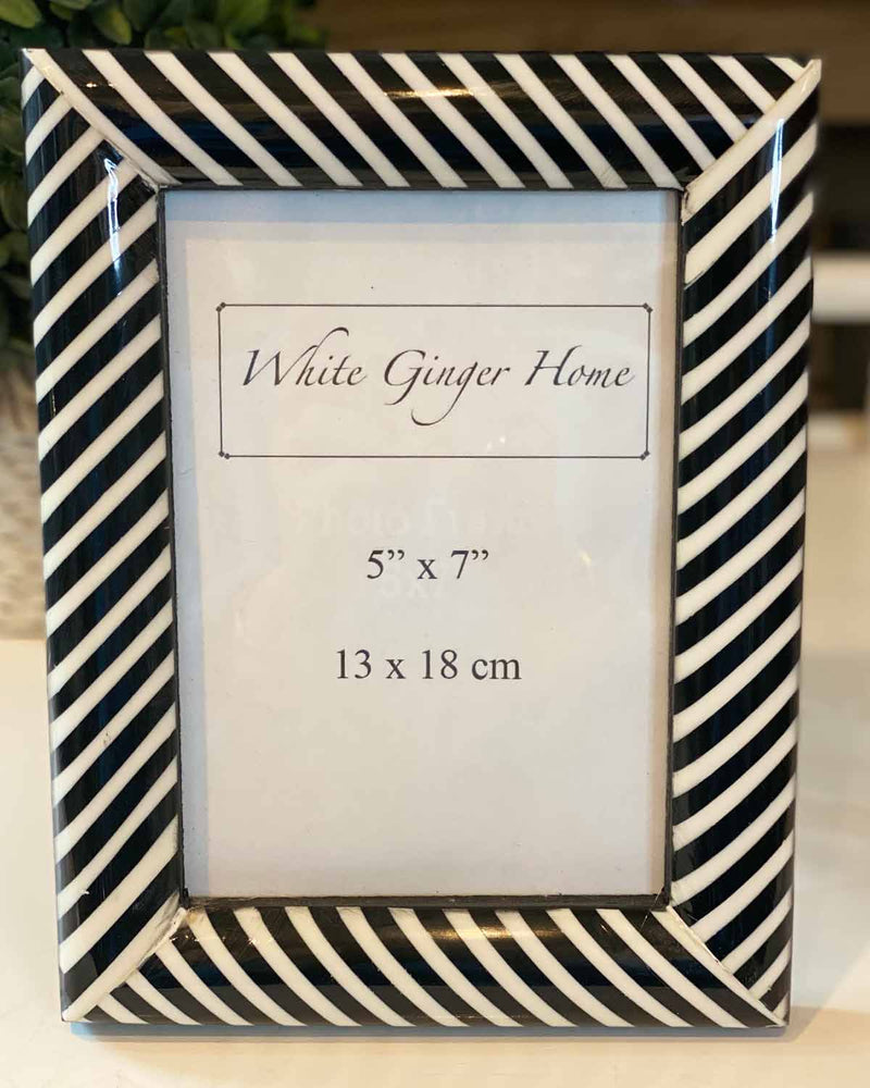 Large black and white striped photo frame, with white inserts. Pictured on white table.