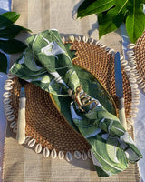 Banana leaf print napkin on rattan shell placemat with brass gecko napkin ring.