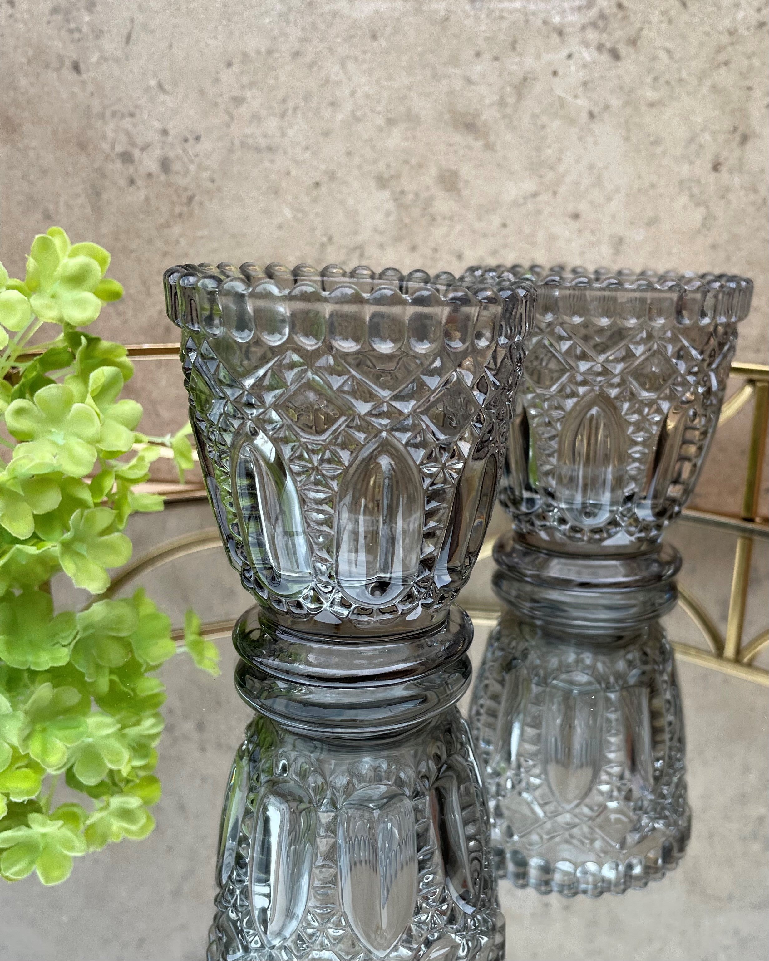 A pair of grey glass tea light holders.