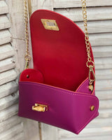 Inside fuchsia cross body bag with gold bamboo clasp. With attachable gold chain.