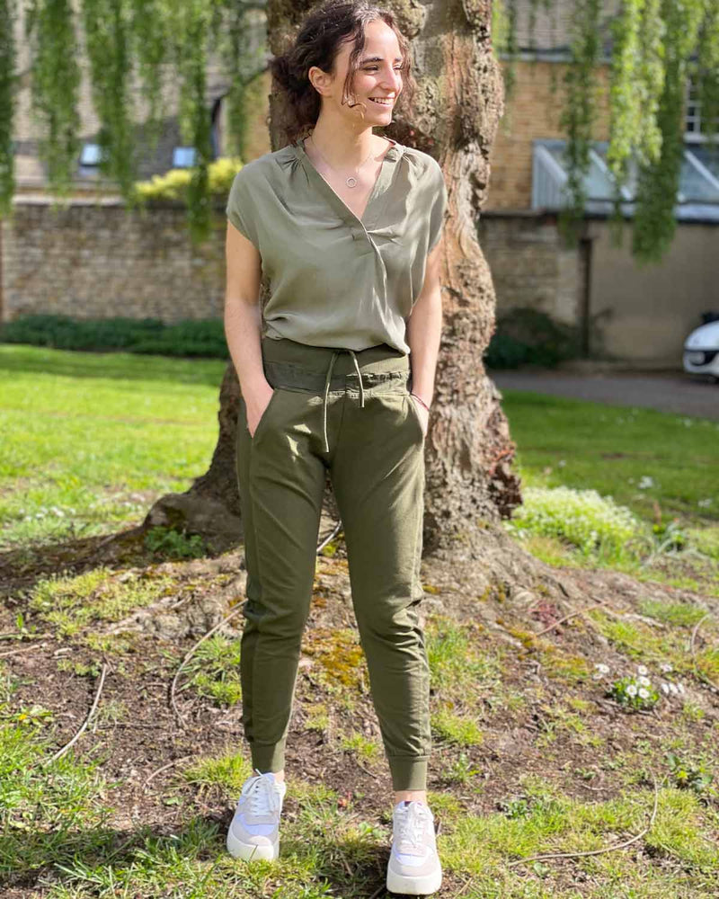 Woman in navy jogger bottoms, paired with white ginger Amanda khaki top and trainers. Perfect for summer in Stamford.
