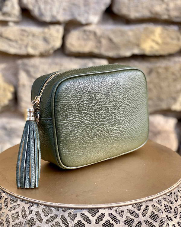 Khaki leather rectangle bag with side tassel on a gold side table.