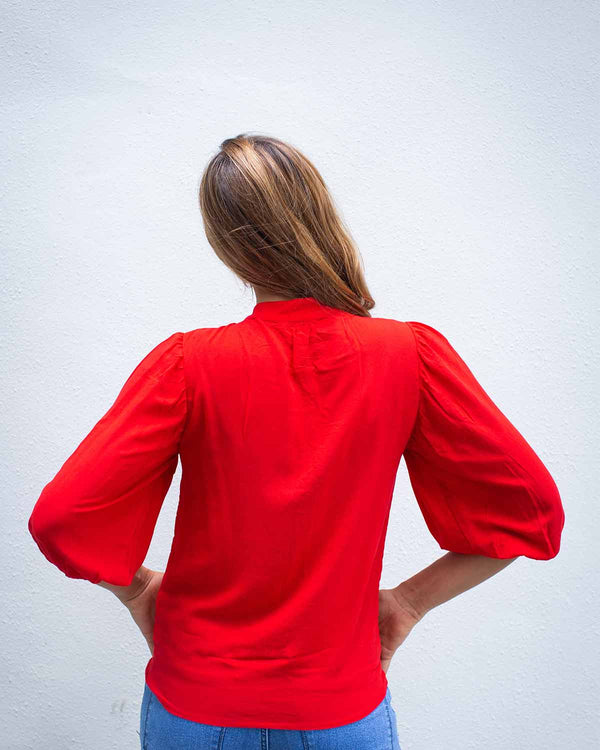 Back image of a woman in a red top with cuffed 3/4 sleeves and a top to bottom button fastening, in a poppy red colour.