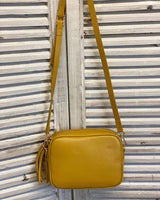 Mustard leather tassel bag with side tassel with adjustable long cross body strap.