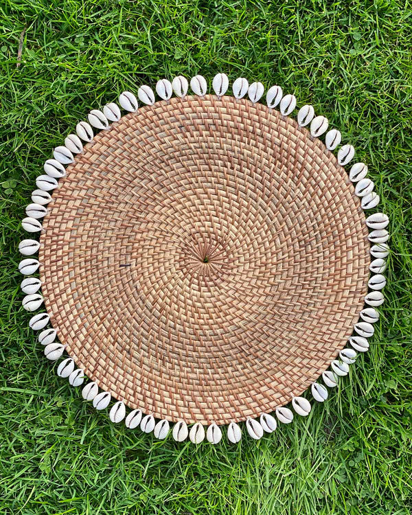 Table placemat in natural rattan edged with sea shells.