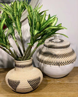 White rattan vase with black triangle design with matching basket and lid.
