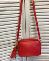 Red leather tassel bag with side tassel with adjustable long cross body strap.