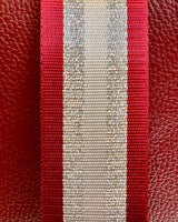 Close up image of red/silver stripe bag strap.