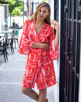 Woman in wrap dress with bell sleeves, printed in a red and white peg tie dye print.