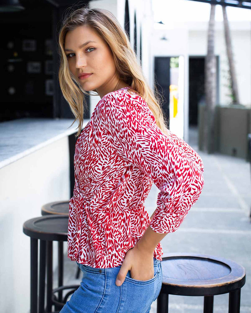 Side image of woman in red and white tiger printed top, with a cross over design at the front and elasticated waist.