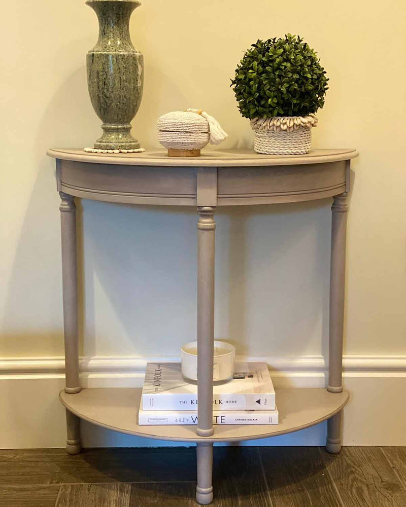 Grey wooden half moon side table with one shelf at the top and one shelf at the bottom.