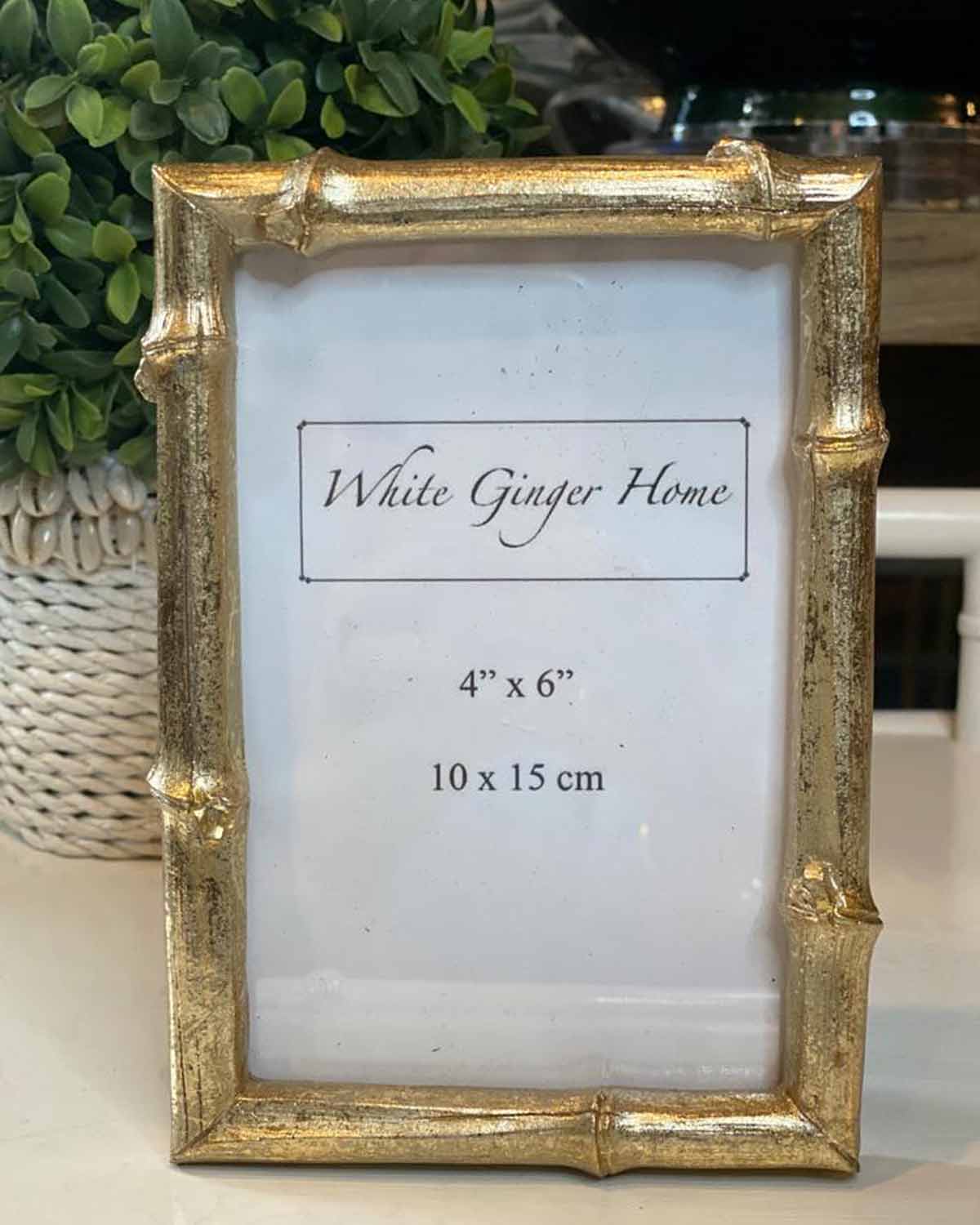 Two gold bamboo effect photo frames in situ on a white desk.