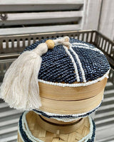 Wooden pot with a beaded top and bottom, with a white bead pattern and tassel on top.