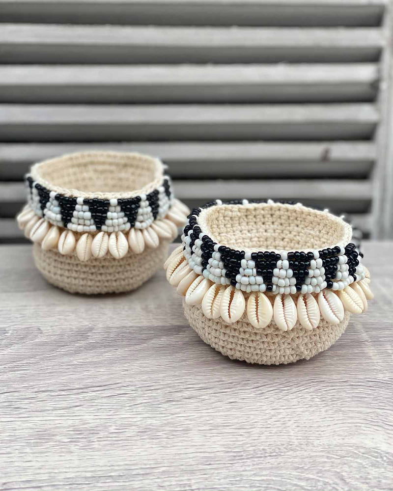 Two woven shell mini baskets, edged with black and white beads shaped as triangles and shells.