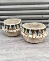 Two woven shell mini baskets, edged with gold and white beads shaped as triangles and shells.