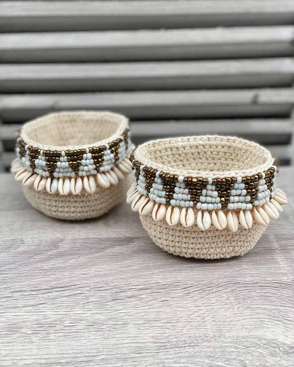 Two woven shell mini baskets, edged with gold and white beads shaped as triangles and shells.