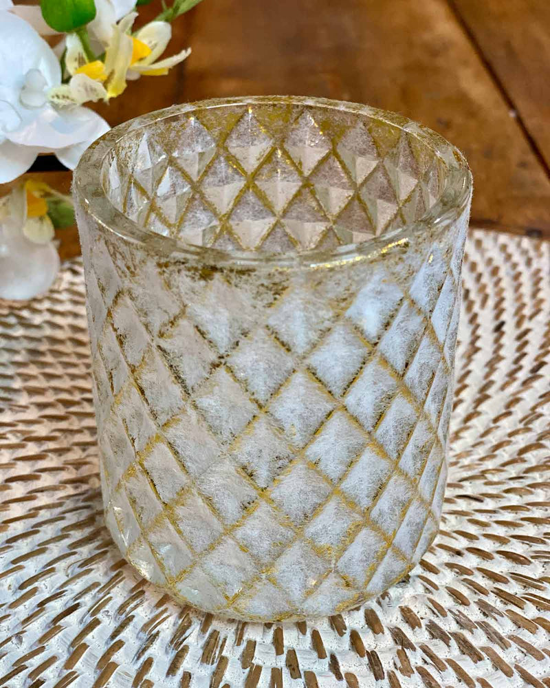A diamond effect gold edged tea lights on a white rattan placemat.