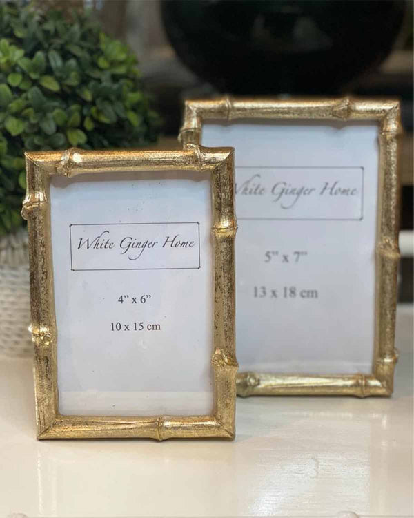 Two gold bamboo effect photo frames in situ on a white desk.
