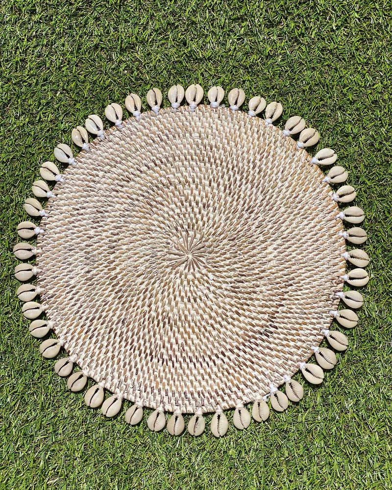 Table placemat in coloured white rattan edged with sea shells.