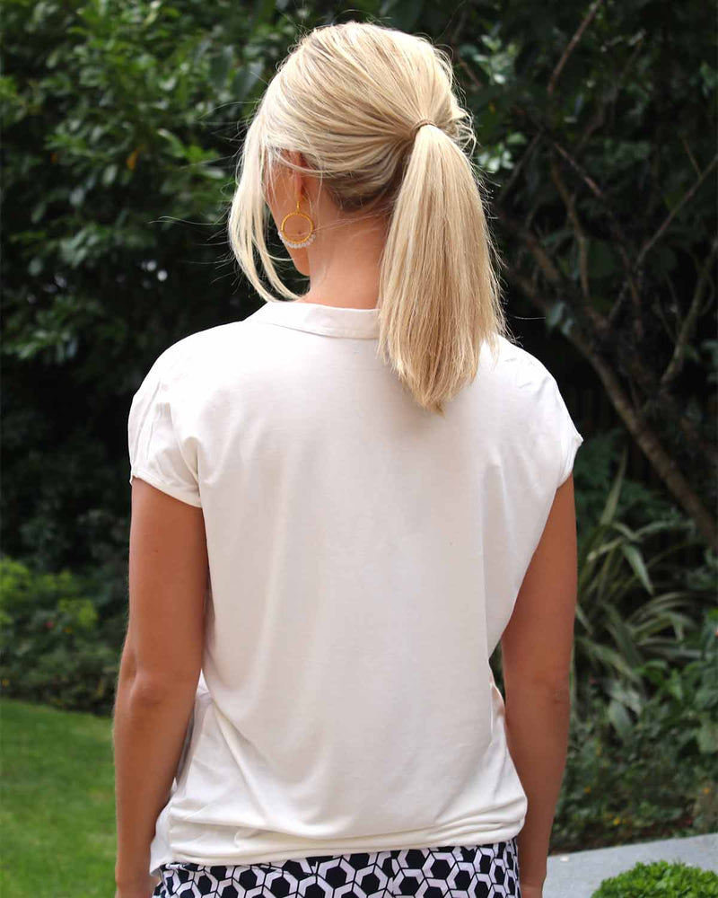 Behind image of woman in short sleeved white blouse.