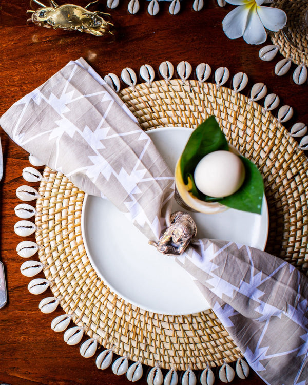 Natural placemat edged with shells, pictured with plate and napkin.