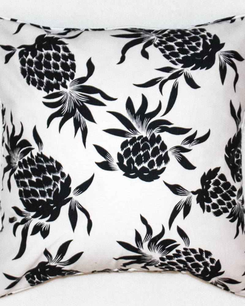 Cushion cover printed with black pineapples on white cotton fabric.