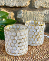 Two honeycomb effect gold edged tea lights on a rattan placemat.