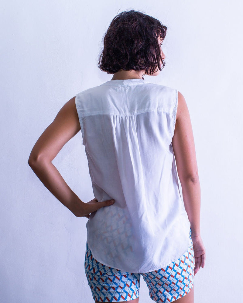 Woman in a sleeveless shirt style top, in the colour white. A womans fashion staple.